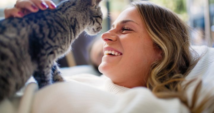 Young woman lying on the bed resting with her cat.